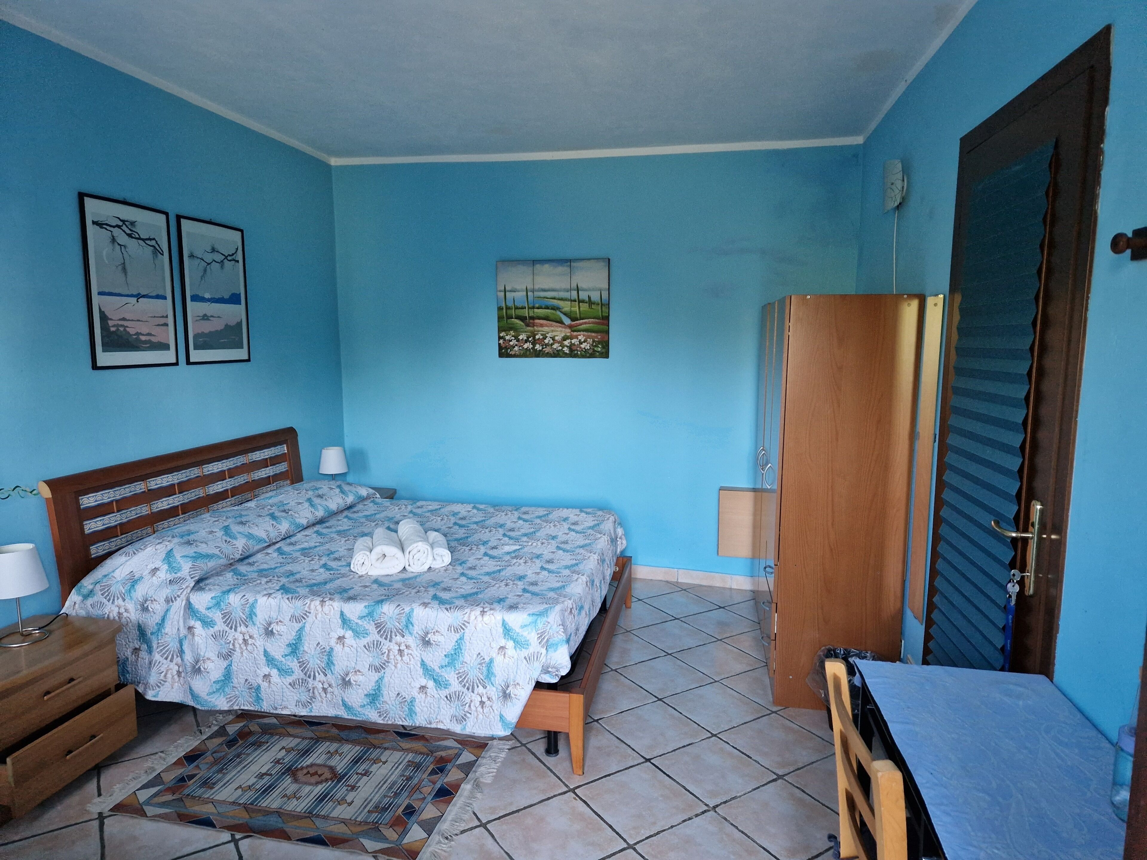 Un dormitorio con cama, un armario de madera, una mesita de noche y una pequeña mesa.