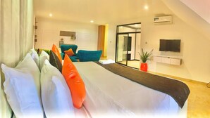 Quarto de hotel moderno com uma cama grande, televisão fixada na parede e porta de vidro deslizante para uma varanda.