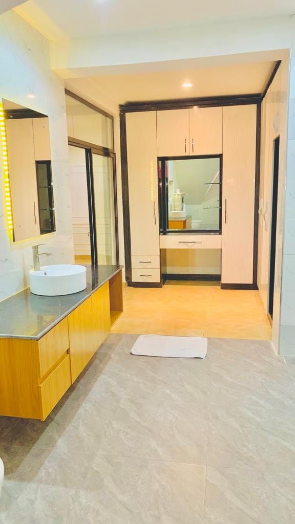 A modern bathroom with a large mirror, a round sink, and a walk-in shower.