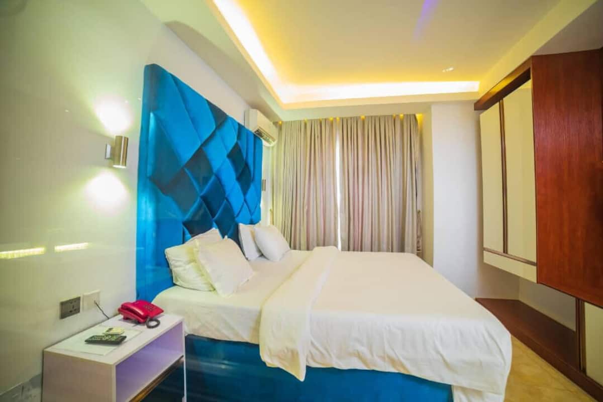 A hotel room with a bed, a nightstand, a telephone, and a curtain.