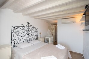 A bedroom with a bed, a crib, a nightstand, and a wardrobe.
