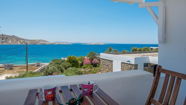 A balcony with a view of the sea, two mugs, and a wooden chair. - Beautiful Apartment With Amazing View In Mykonos Old Town (Mykonos)