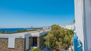 A coastal building with a stone facade, a blue staircase, and a view of the sea and distant buildings. - Lovely Studio In Mykonos Old Town (Mykonos)