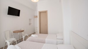 A hotel room with two beds, a TV mounted on the wall, a small table, and two white chairs. - Lovely Studio In Mykonos Old Town (Mykonos)
