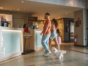 Zona de recepción de un hotel con mostrador, extintor y un perro en el suelo.