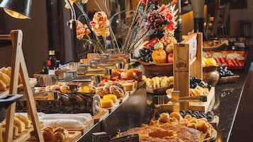 Un bufé con diversos alimentos, un arreglo floral y una iluminación moderna.