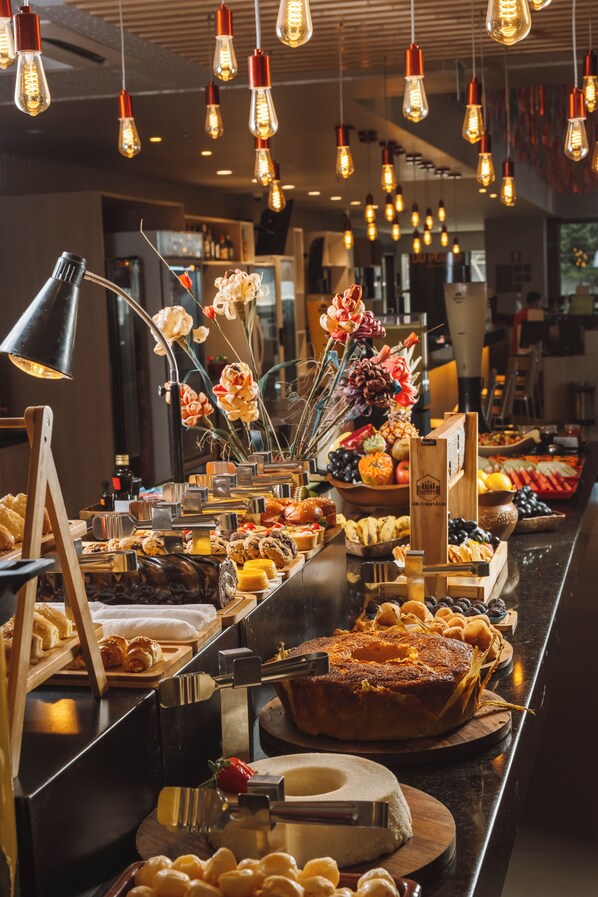 Un bufé con diversos alimentos, un arreglo floral y una iluminación moderna.
