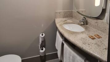 Ein Badezimmer mit Toilette, Waschbecken, Spiegel und einer Toilettenpapierrolle.