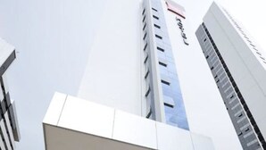 Een modern gebouw met een opvallende trap die naar de ingang leidt, een glazen gevel en een bord met de tekst 