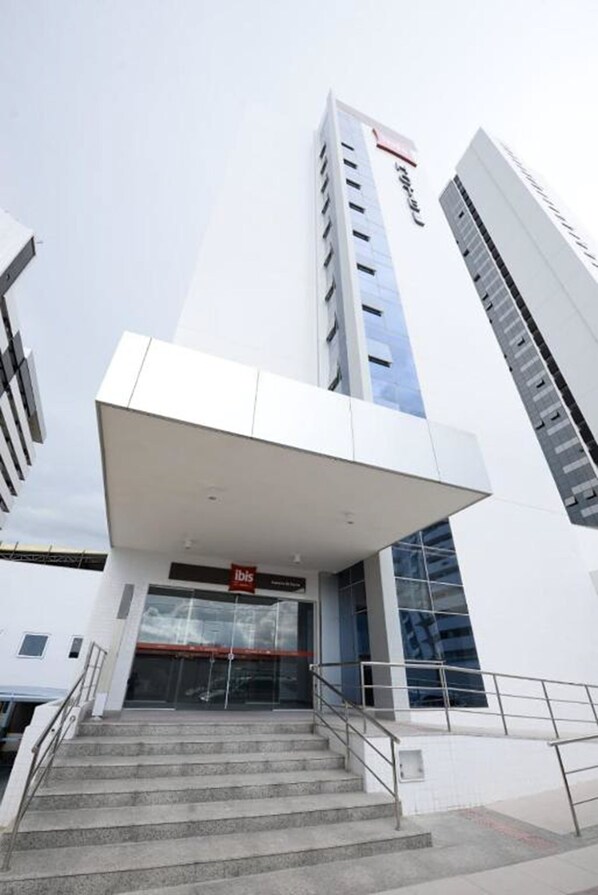 A modern building with a prominent staircase leading to the entrance, a glass facade, and a sign that reads "ibis." - ibis Juazeiro do Norte (Juazeiro do Norte)