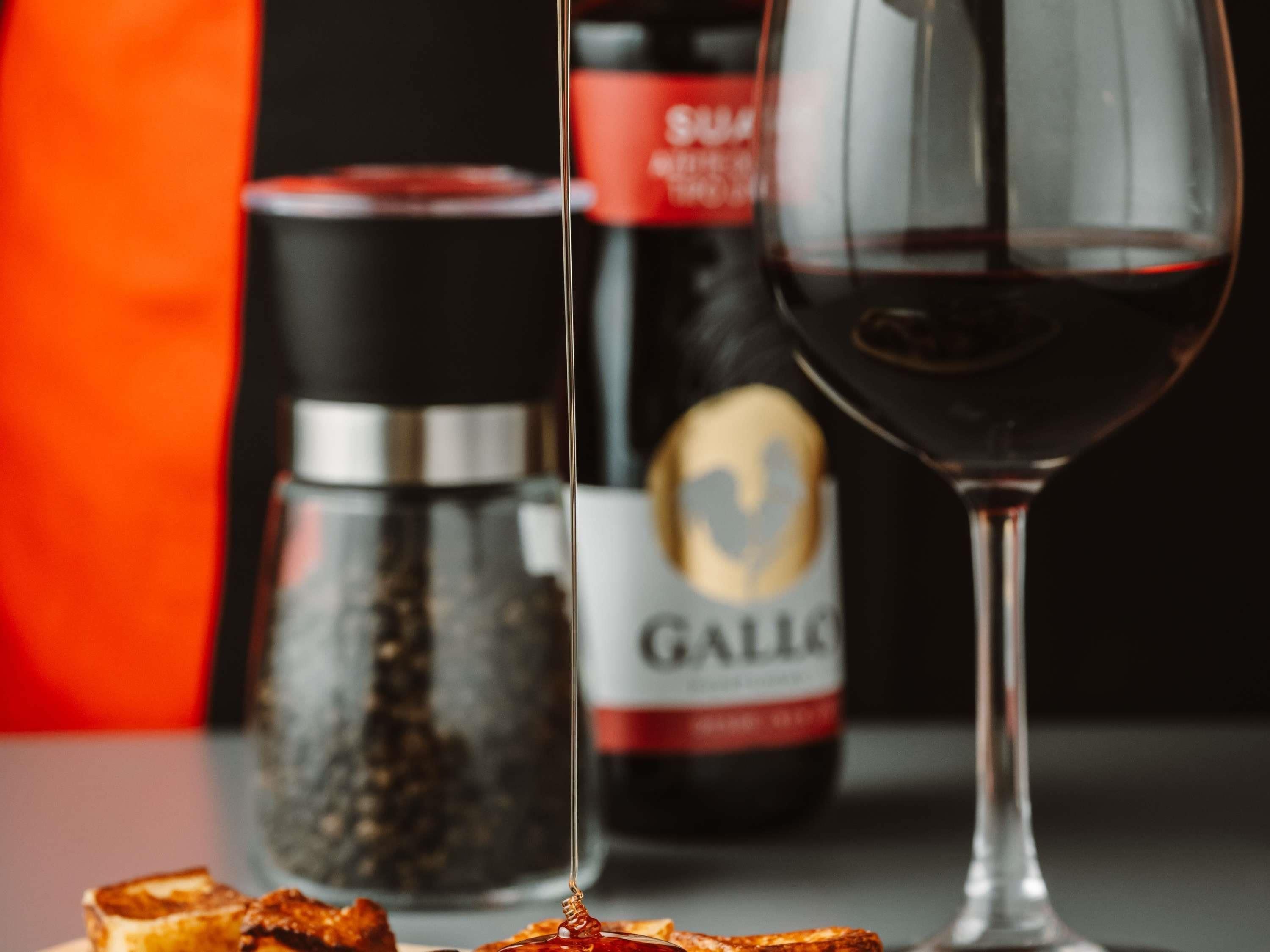 Um copo de vinho tinto, um saleiro e uma garrafa de vinho com etiqueta.