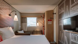 Een hotelkamer met een bed, televisie, bureau en raam met uitzicht.
