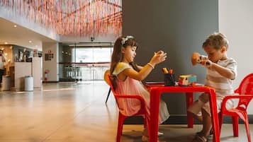 A spacious indoor area with a high ceiling and a modern design, featuring a dining table with chairs and a small table with toys.
