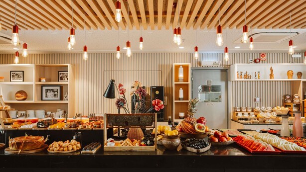 Een buffetgedeelte met diverse gerechten en een houten plafond met hangende lampen.
