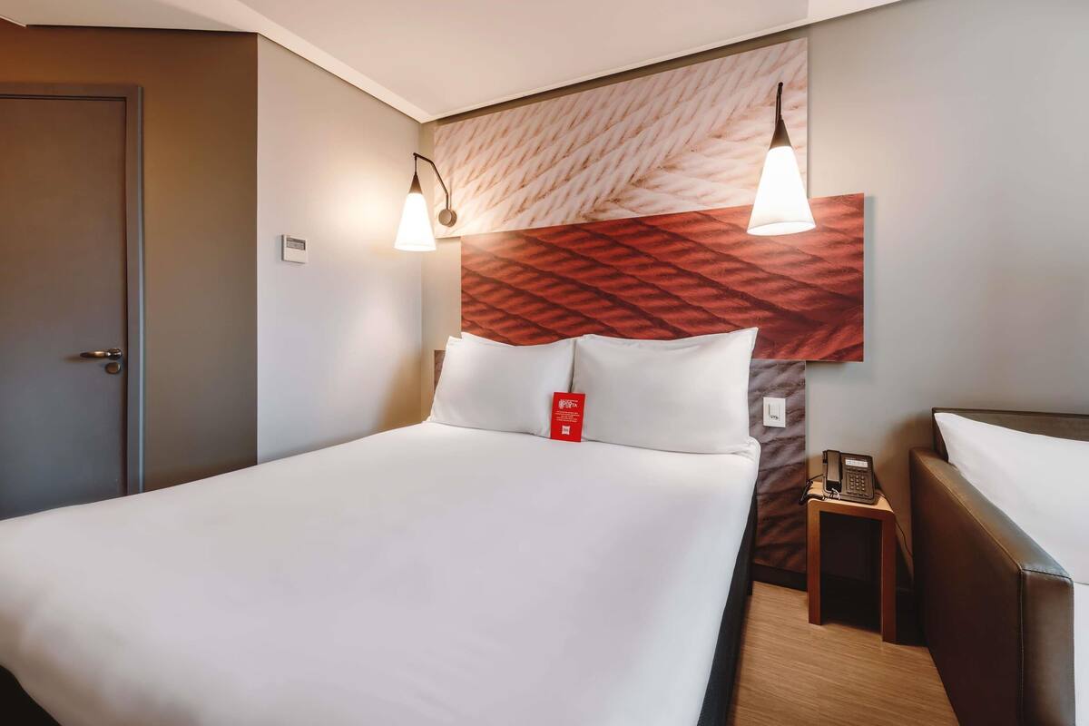 Ein Hotelzimmer mit Bett, Nachttischen, Telefon und Tür.