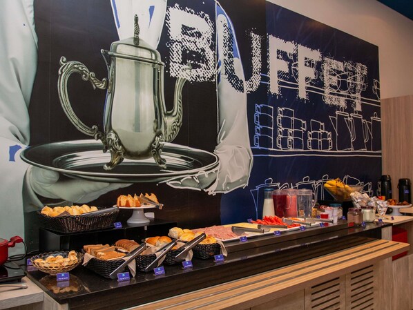 Un buffet proposant une variété de plats, avec en arrière-plan une grande fresque murale sur le thème du café.