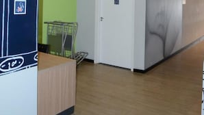 Et hotellobby med en receptionsdisk, en grøn væg, en hvid dør og en væg med et stort muralmaleri.