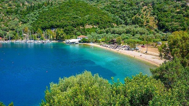 Une zone côtière avec une plage, des bateaux et un petit bâtiment.