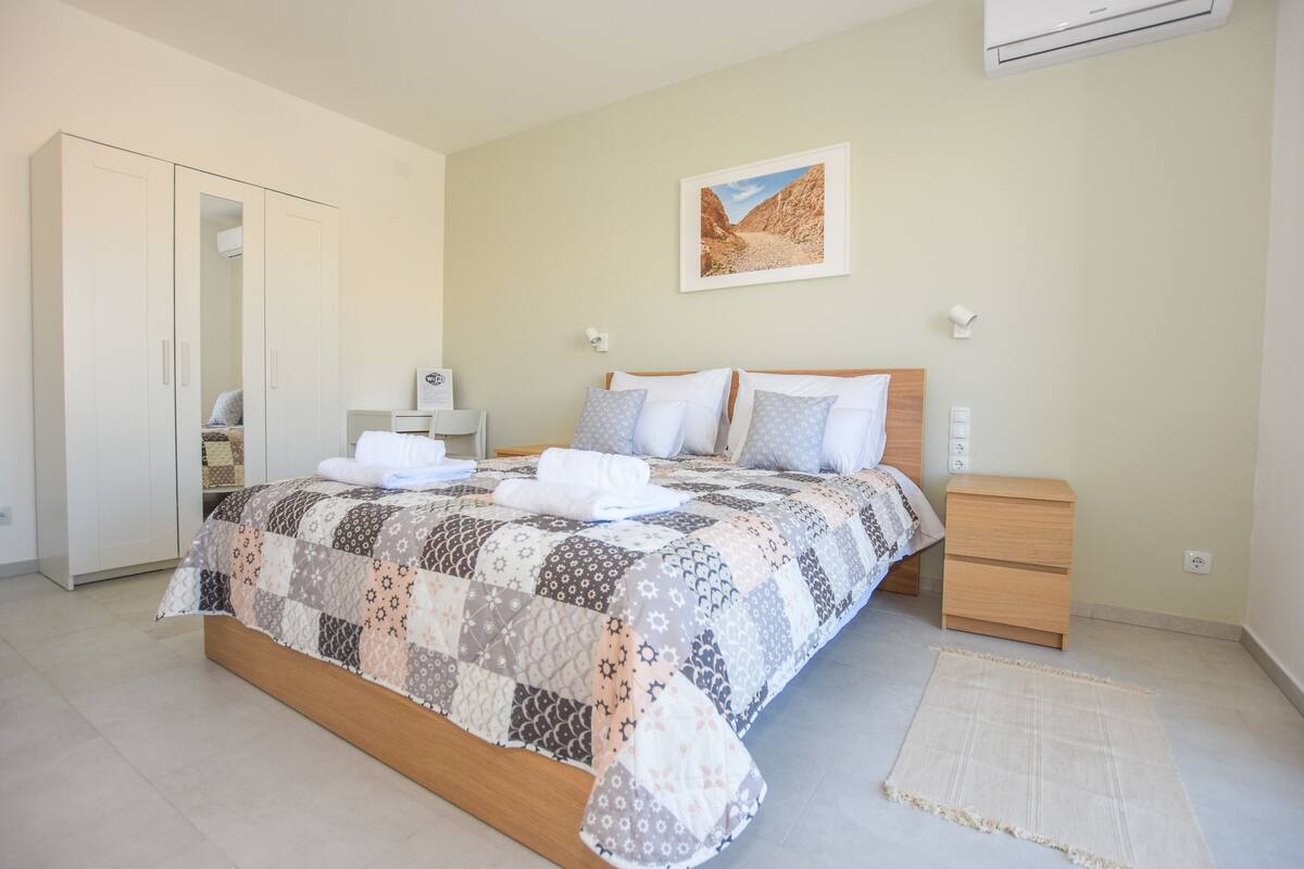A bedroom with a bed, a nightstand, a wardrobe, and a painting on the wall.