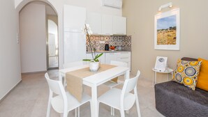 A modern kitchen with white cabinets, a tiled backsplash, and a dining area with a white table and chairs. - Apartments Villa Magena (Pag)