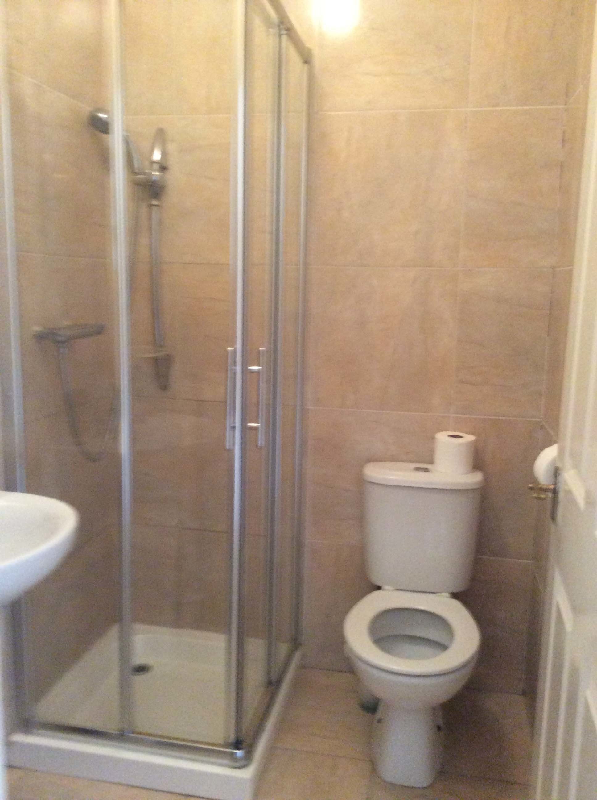 Un baño pequeño con ducha de vidrio, inodoro y lavamanos.