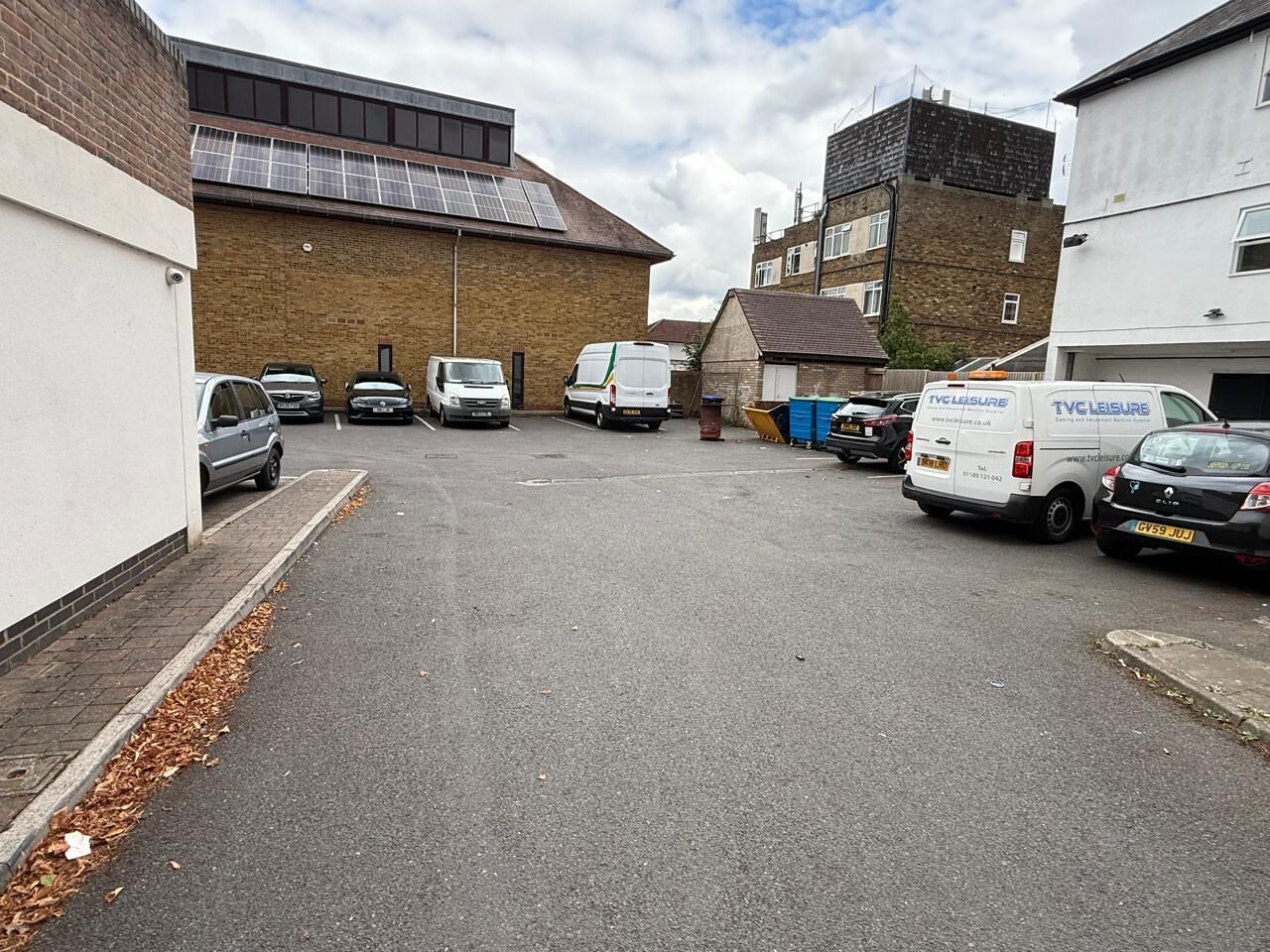 A parking lot with several cars and vans, including a white van with 'TVC Leisure' branding.