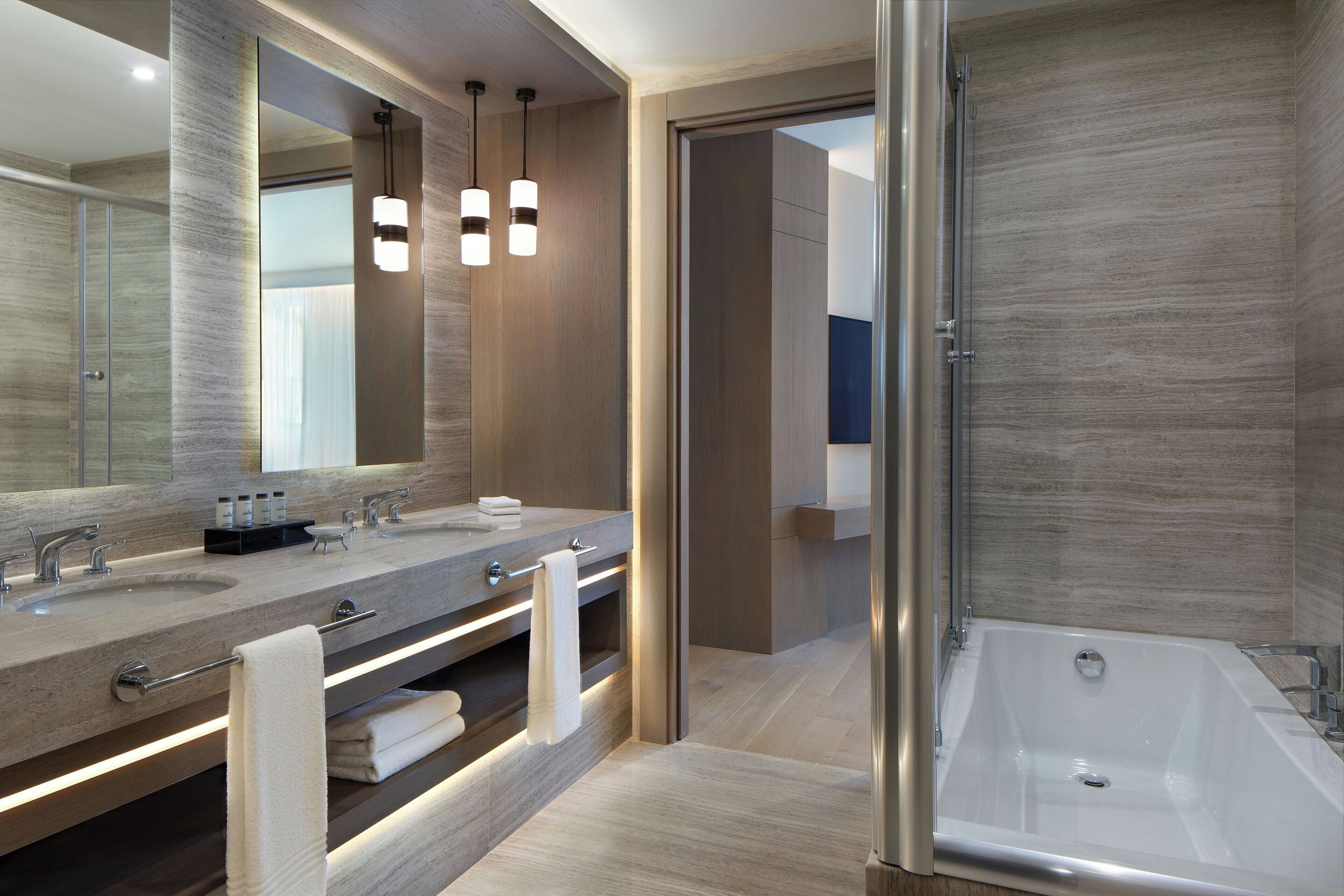 A modern bathroom with two sinks, a large mirror, and a walk-in shower.