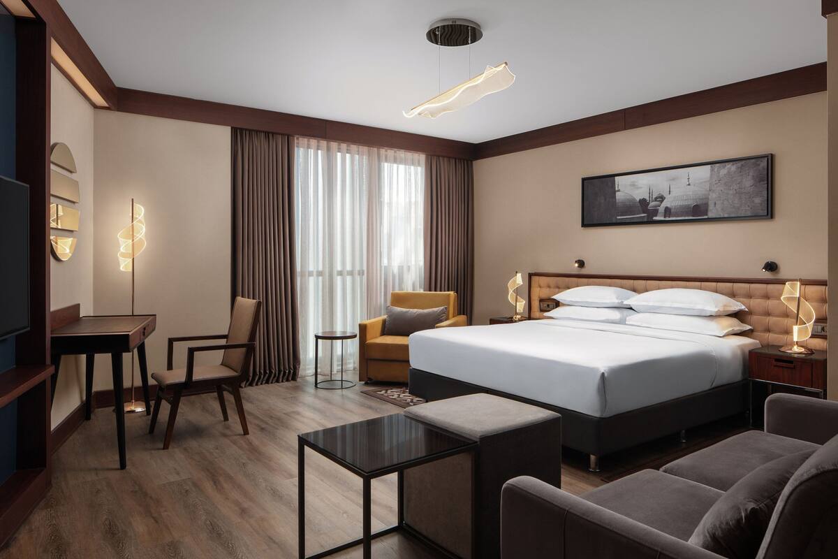Una habitación de hotel con una cama grande, un escritorio, una silla, un sofá y un televisor.