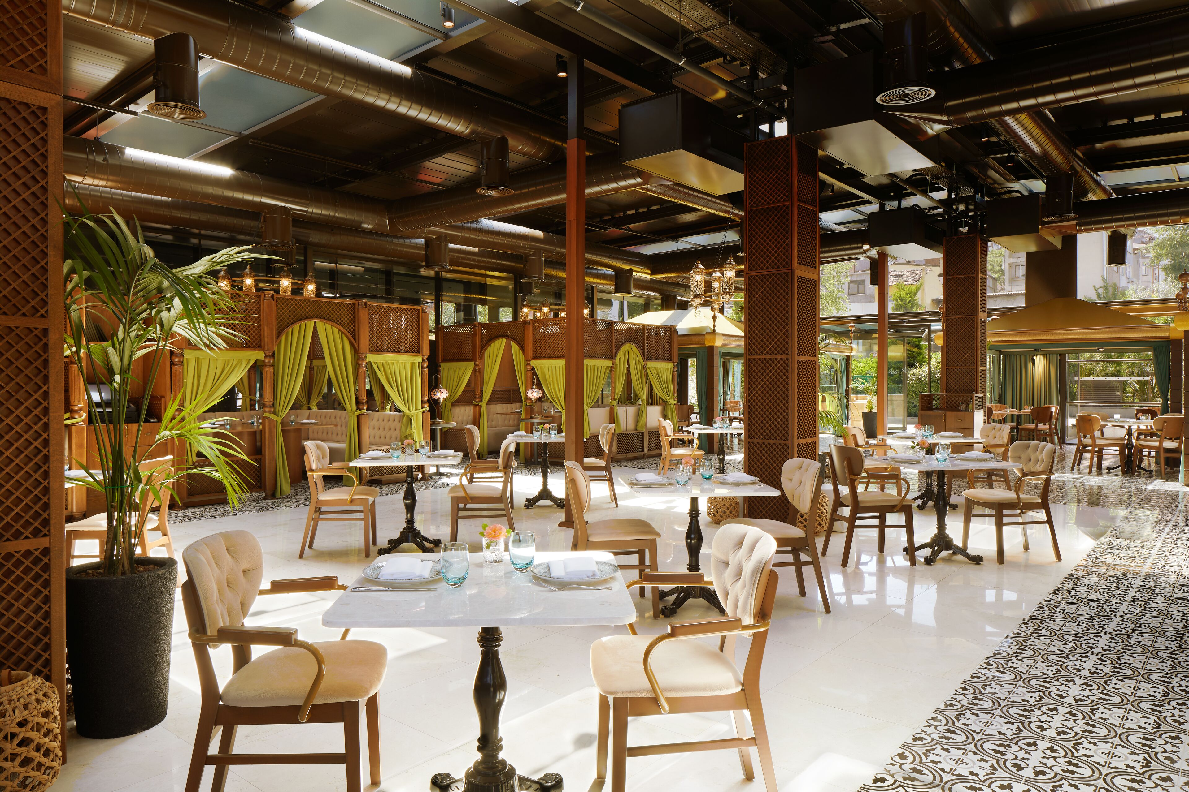 A spacious restaurant with high ceilings, exposed ductwork, and a variety of seating arrangements including tables and chairs.