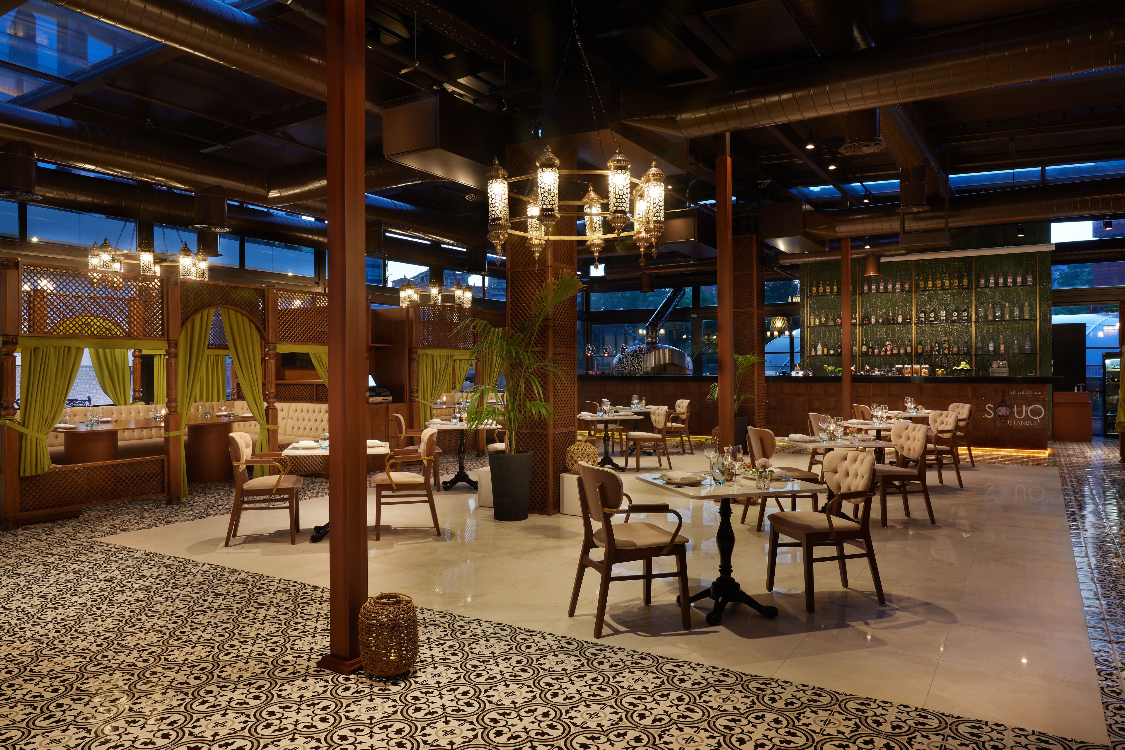 A spacious restaurant with high ceilings, ornate chandeliers, and a variety of seating arrangements.
