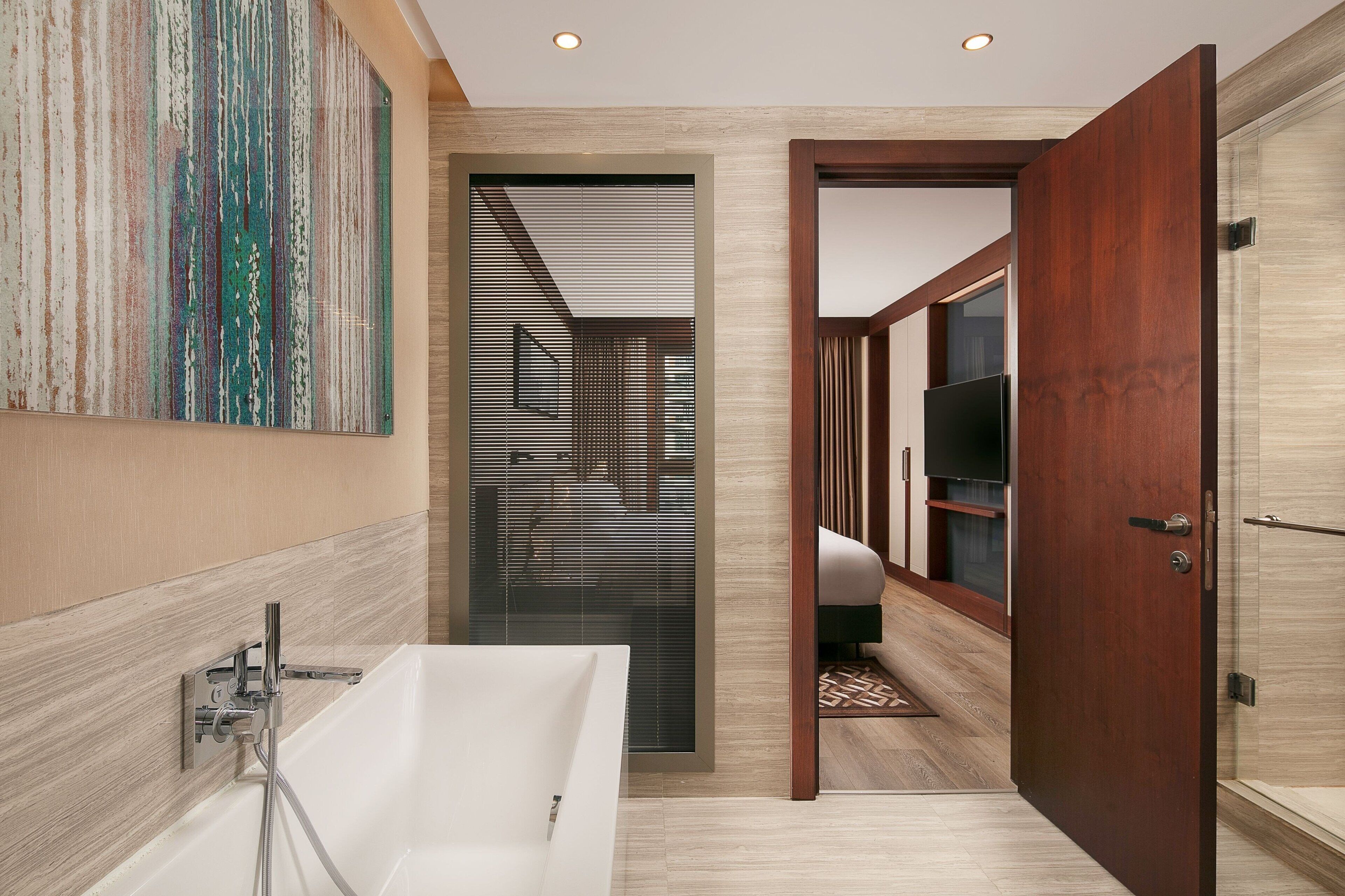 A modern bathroom with a bathtub, wooden paneling, and a large mirror.
