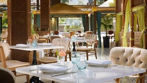 A restaurant with tables set for dining, chairs, and a decorative vase with flowers. - Sheraton Istanbul City Center (Istanbul)