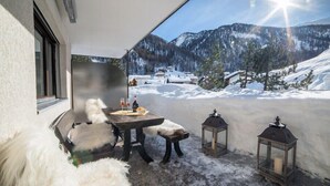 A cozy outdoor seating area with a table, two chairs, and two lanterns.