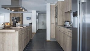 A modern kitchen with wooden cabinetry, a stainless steel refrigerator, and a built-in oven.