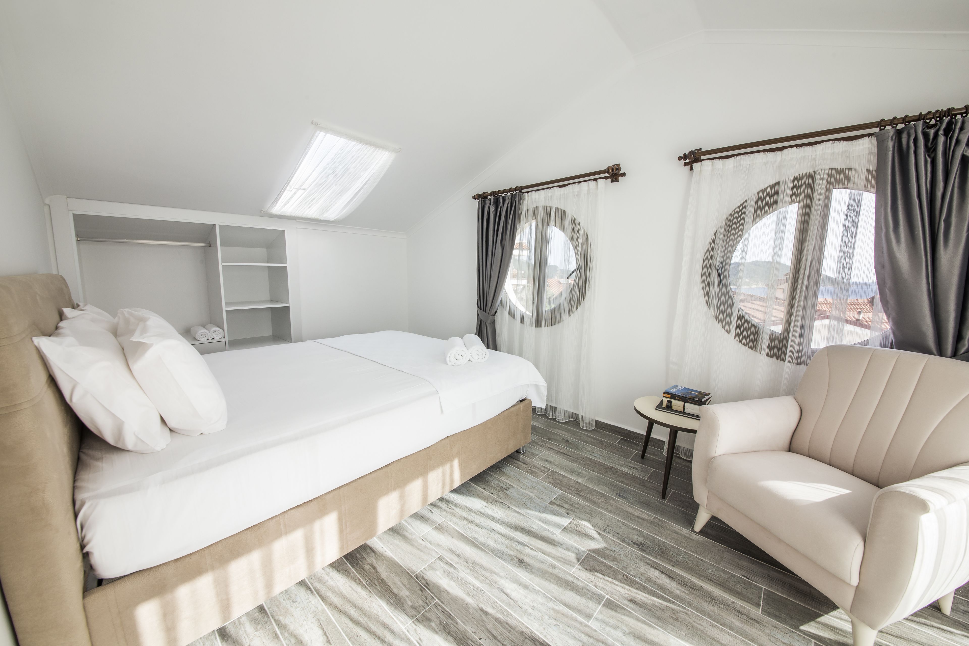 Quarto com cama, sofá, mesinha, guarda-roupa e janela com cortinas.