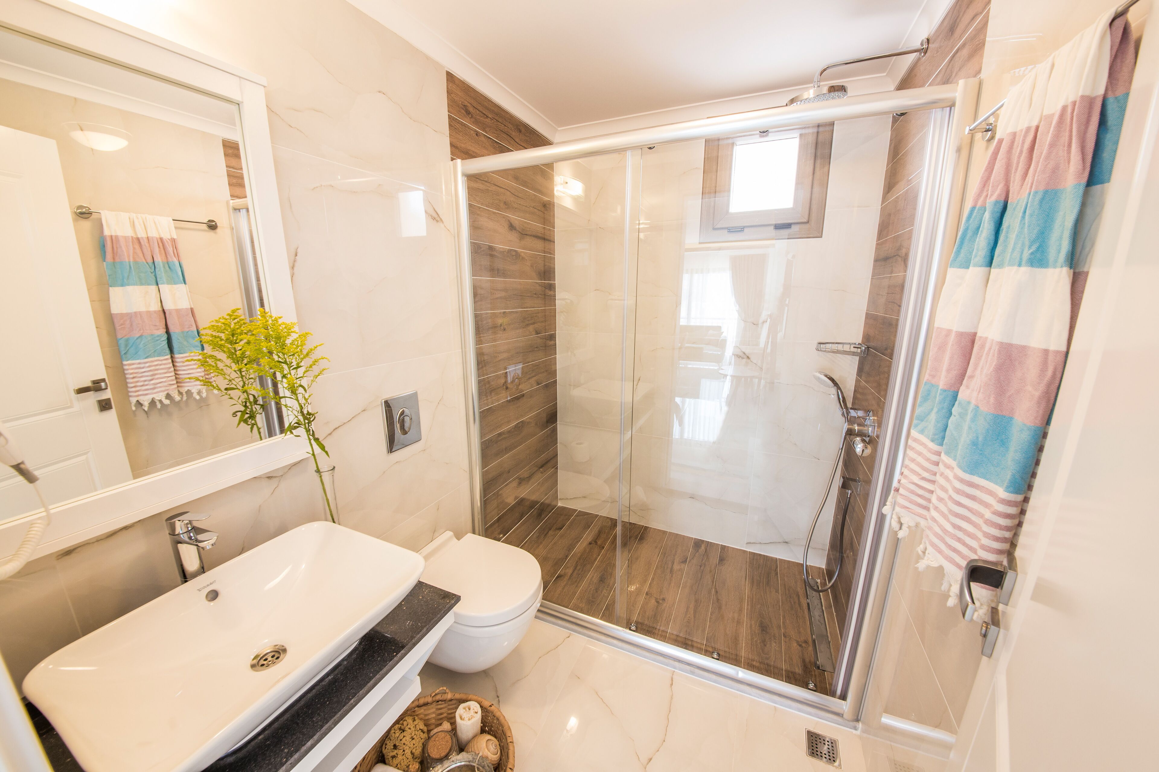 A modern bathroom with a glass-enclosed shower, a white sink, and a toilet.