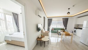 A modern hotel room with a bed, a dining area, a kitchen, and a living area. - Cedrus Suites (Kas)