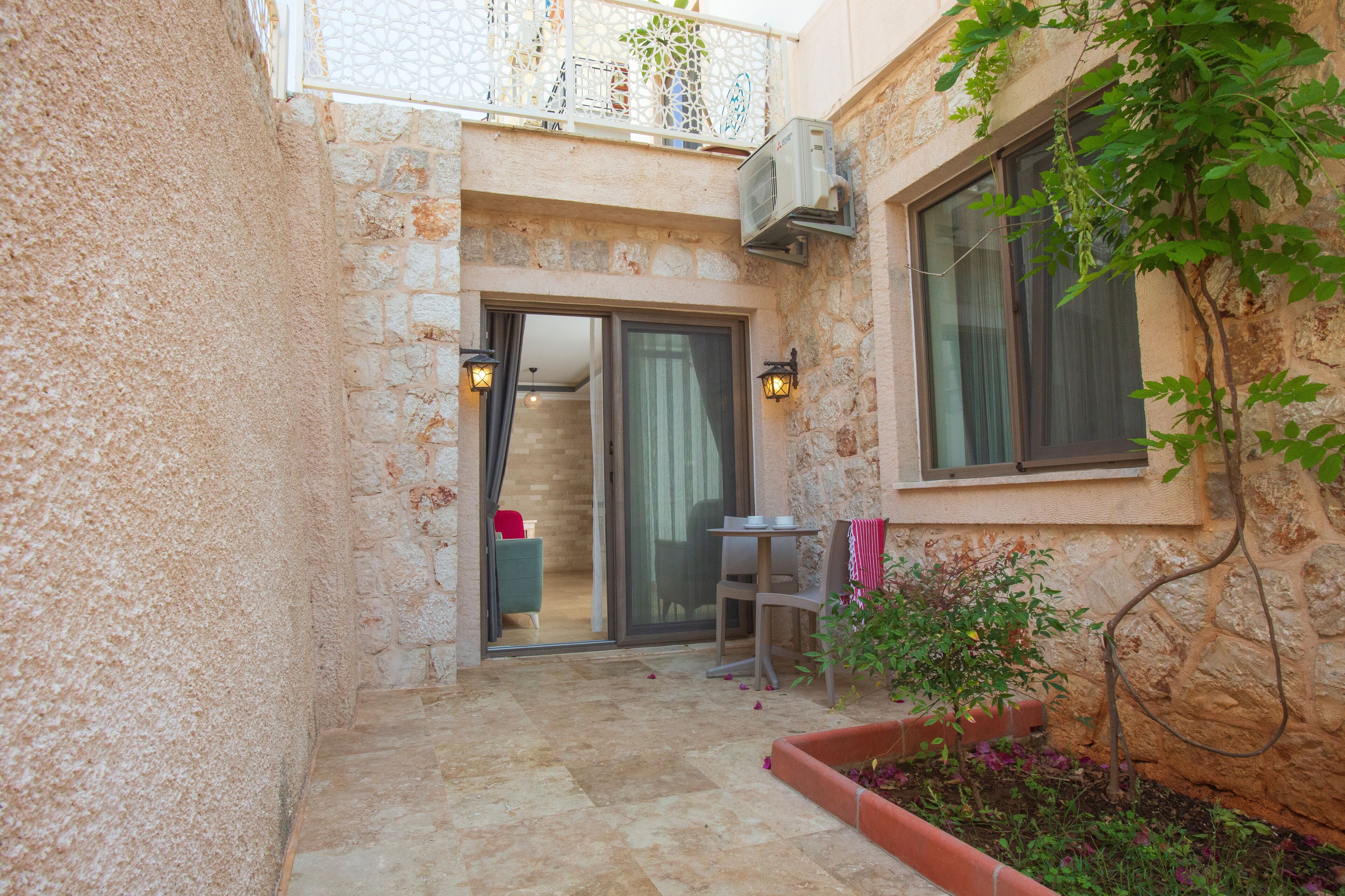 A stone building with a small patio area, a sliding glass door, and a small table with chairs.