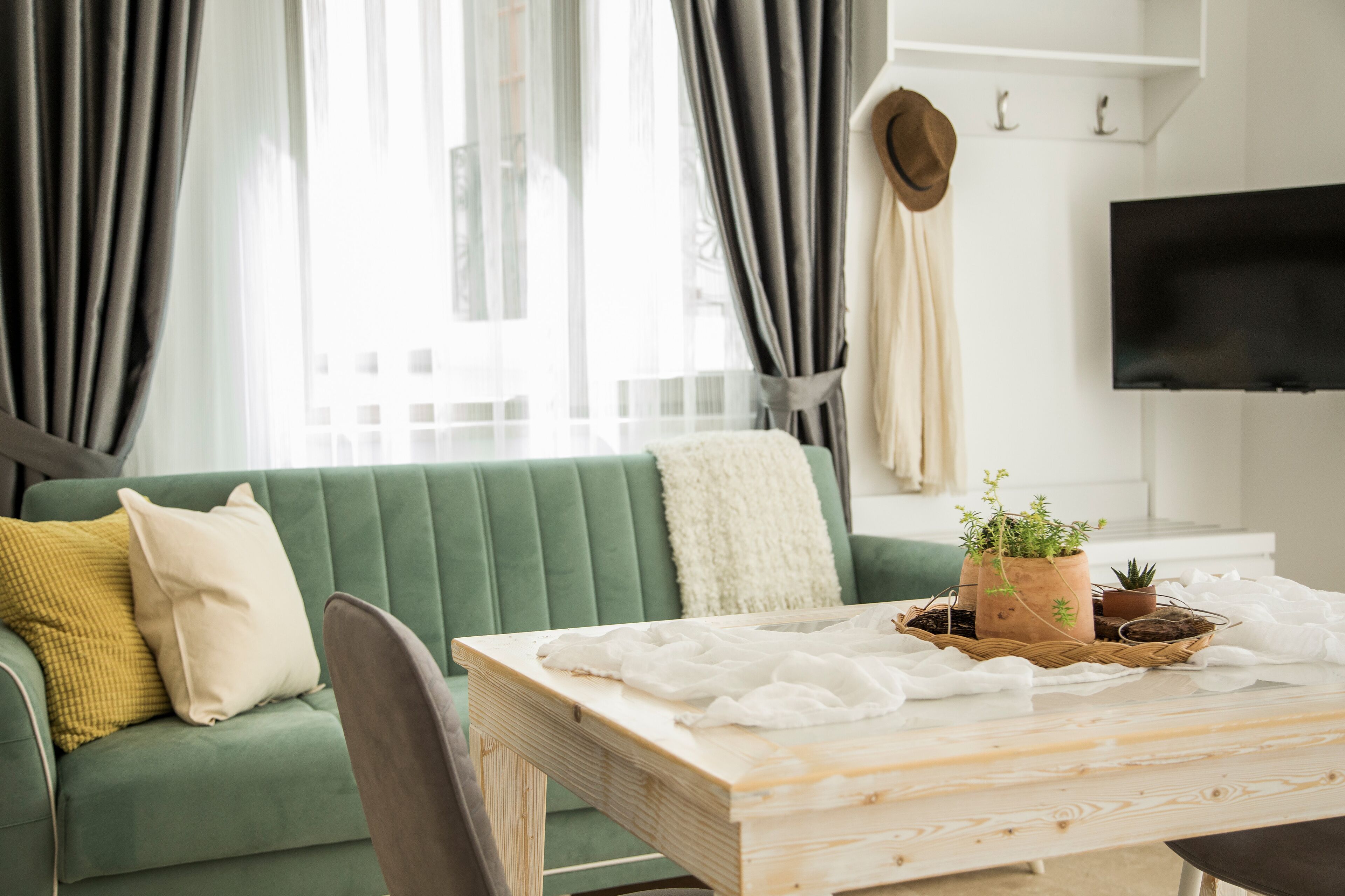A modern living room with a green sofa, a wooden coffee table with a white cloth, and a potted plant.