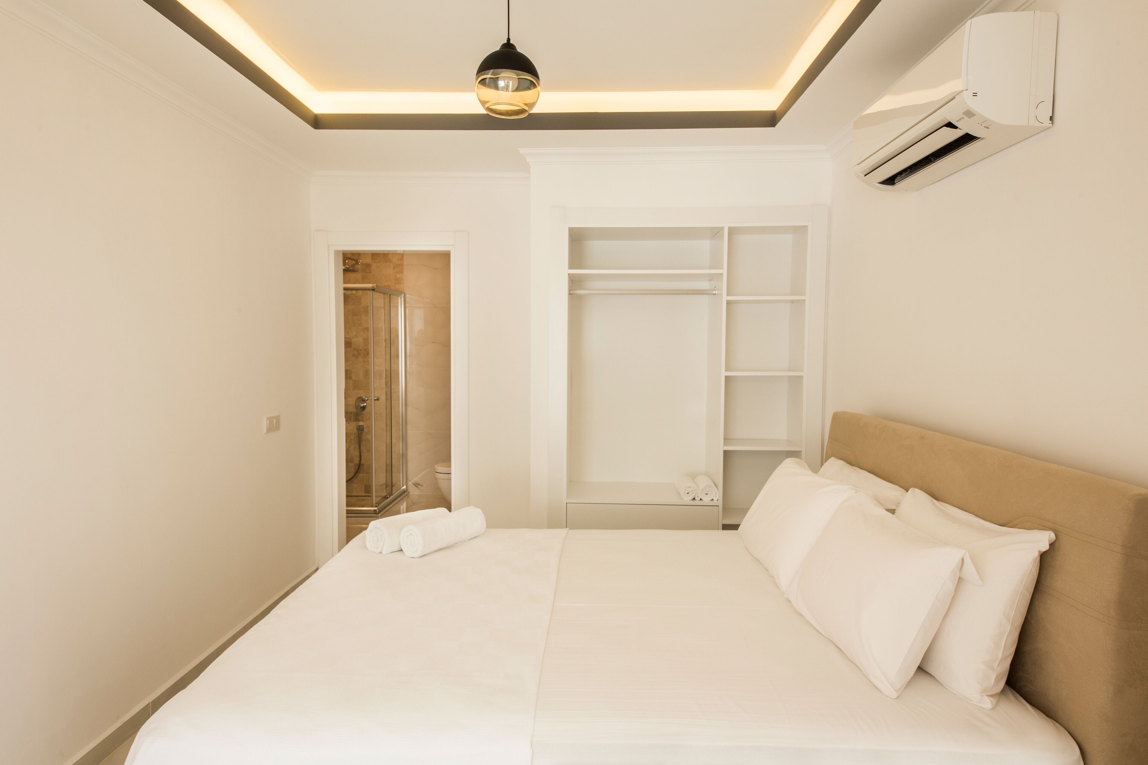 A hotel room with a bed, a wardrobe, and an air conditioning unit.