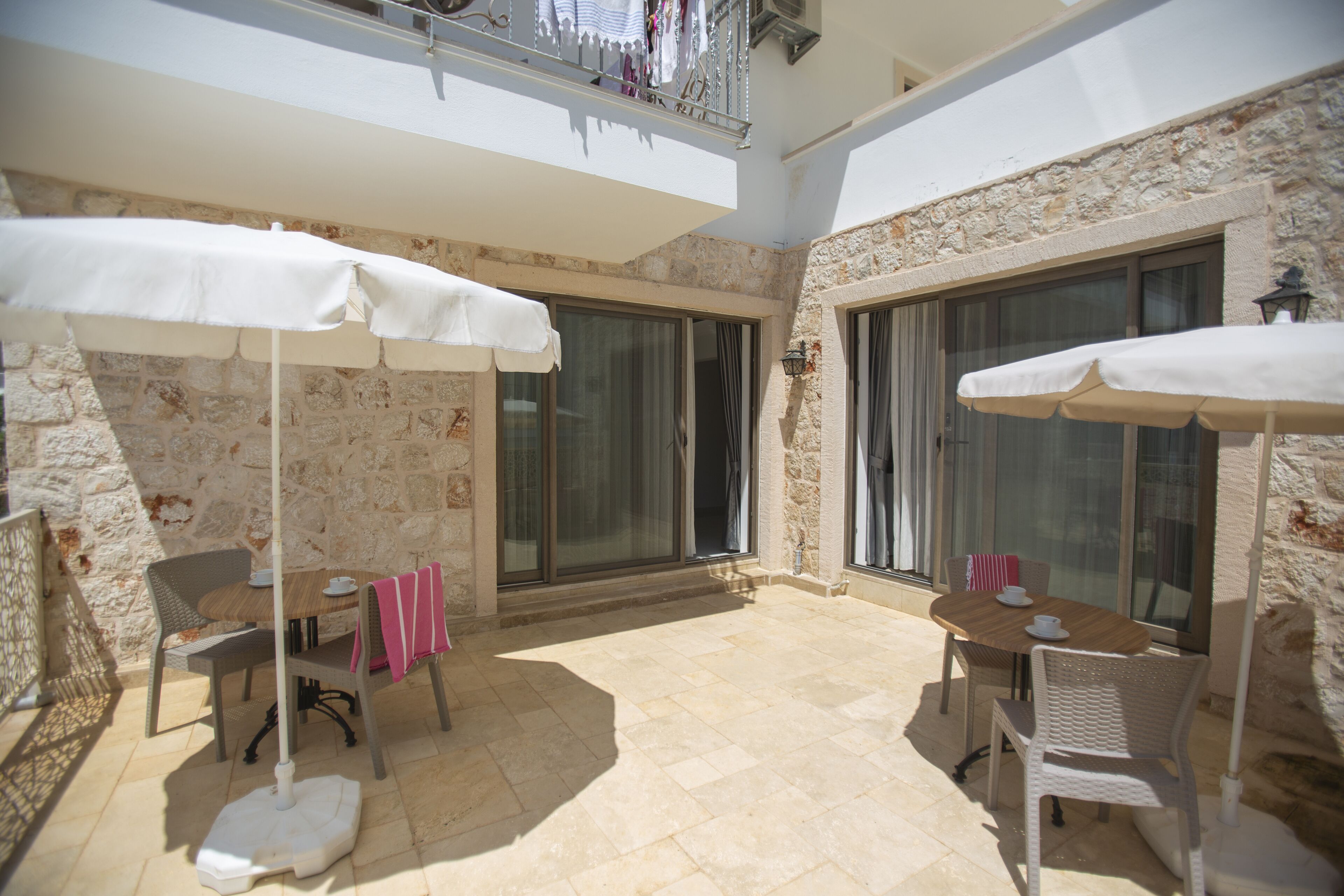 An outdoor patio with two tables, chairs, and umbrellas.