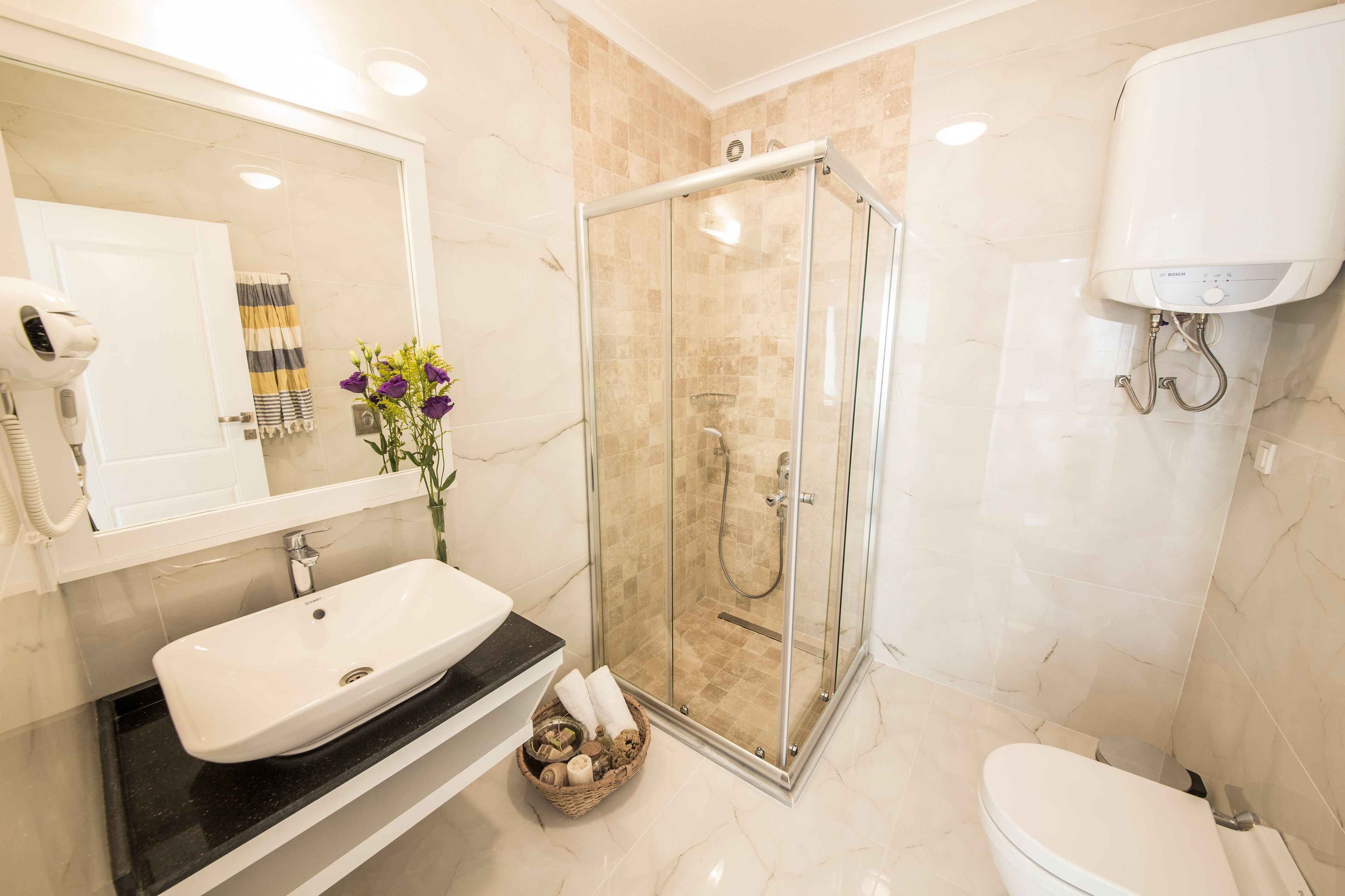 A bathroom with a glass-enclosed shower, a white sink, and a toilet.