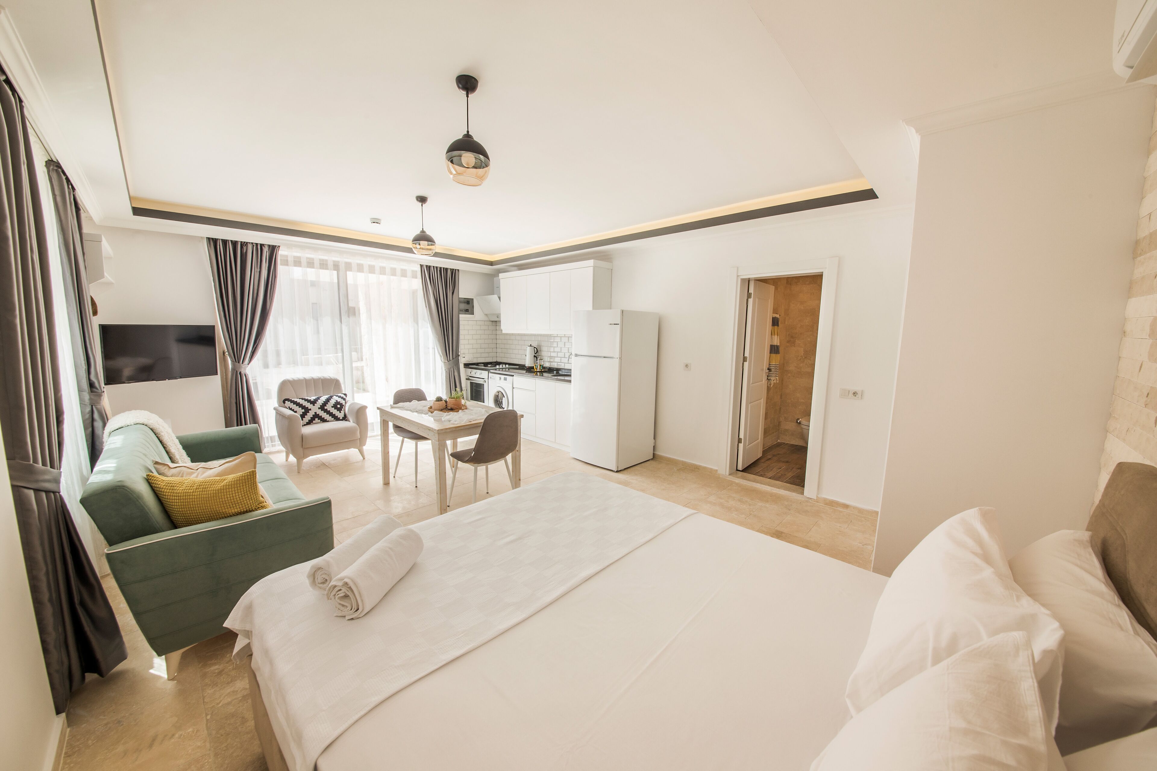 Una habitación de hotel moderna con una cama grande, un escritorio, una silla y una kitchenette.