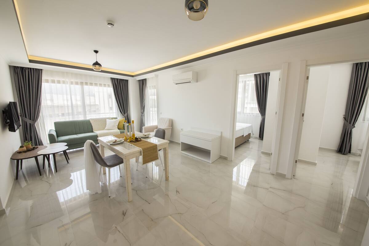 A modern hotel room with a dining area, a sofa, a small table, and a bed.