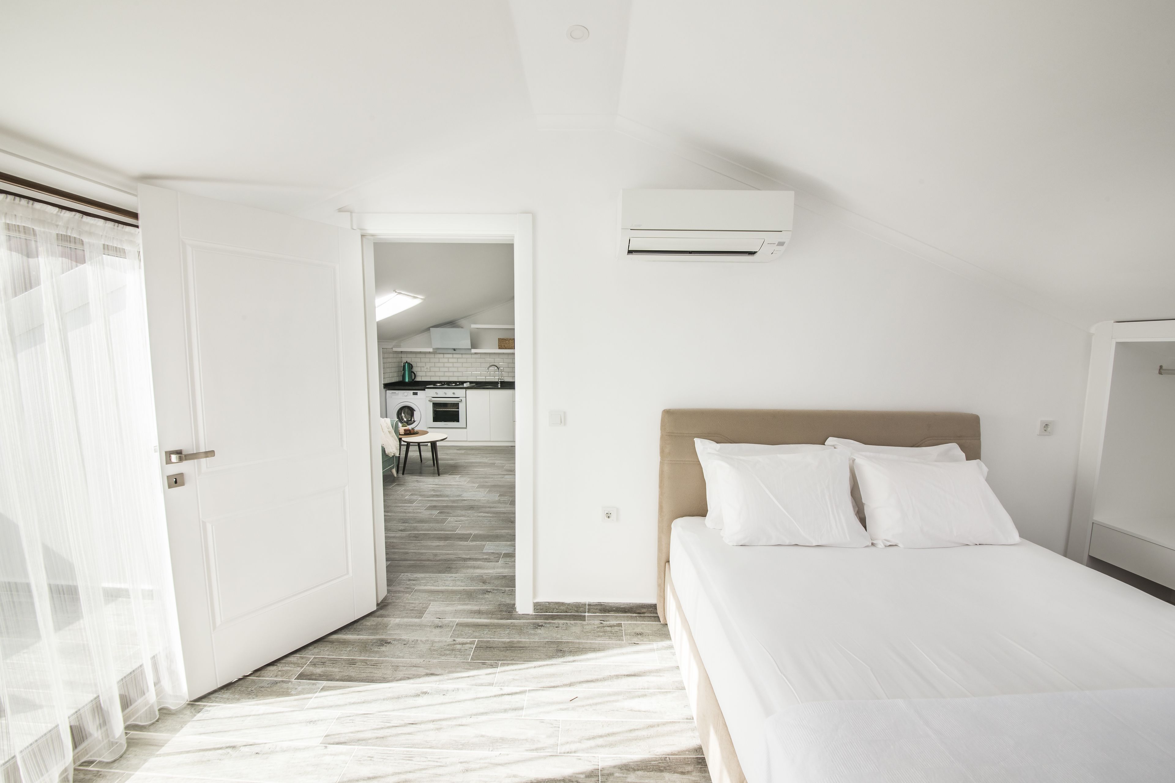 A modern hotel room with a bed, a small kitchenette, and a bathroom.