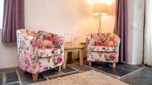 A room with two floral armchairs, a small table, and a floor lamp. - Coombe Farm (Looe)