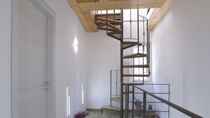 Un interior moderno con una escalera de caracol, vigas de madera y piso de baldosas.