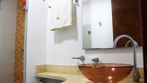 Een badkamer met een glazen wastafel, een wit toilet en een handdoek aan een rek.