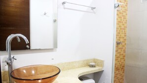 Ein Badezimmer mit einem Waschbecken aus Glas, einer weißen Toilette und einem Handtuchhalter.