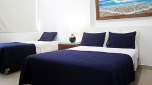 Ein Hotelzimmer mit zwei Betten, einem Nachttisch, einer Lampe und einem Bild mit einer Strandansicht.